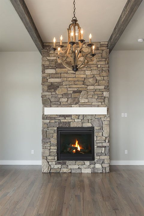 Stone fireplace with exposed beam and chandelier